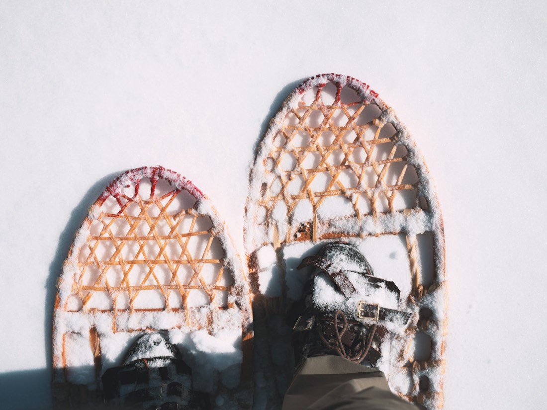 A pair of traditional wooden snowshoes photographed from above in fresh snow